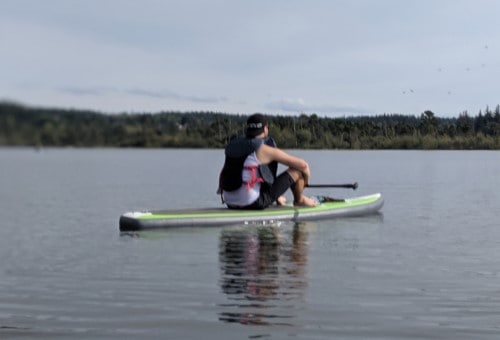 man looking into horizon on paddle board